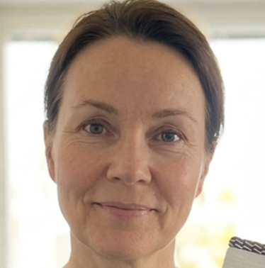A headshot of a middle-aged woman with brown hair smiling gently at the camera.