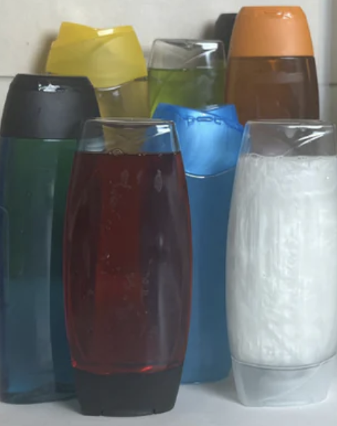 Assorted shampoo bottles in various colors on a surface.