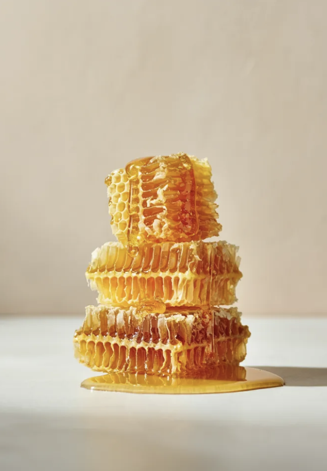 Stack of honeycomb pieces with honey dripping down.