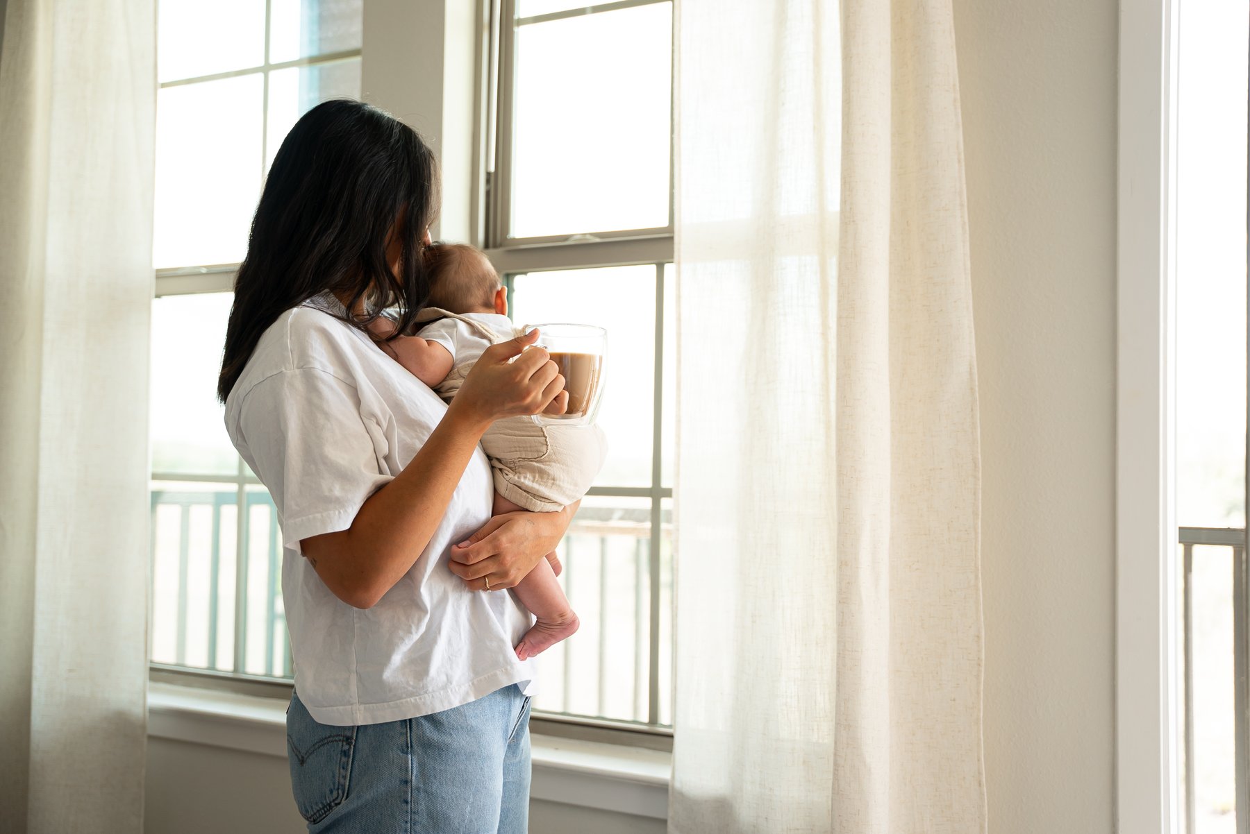 Mom enjoying coffee while holding her baby