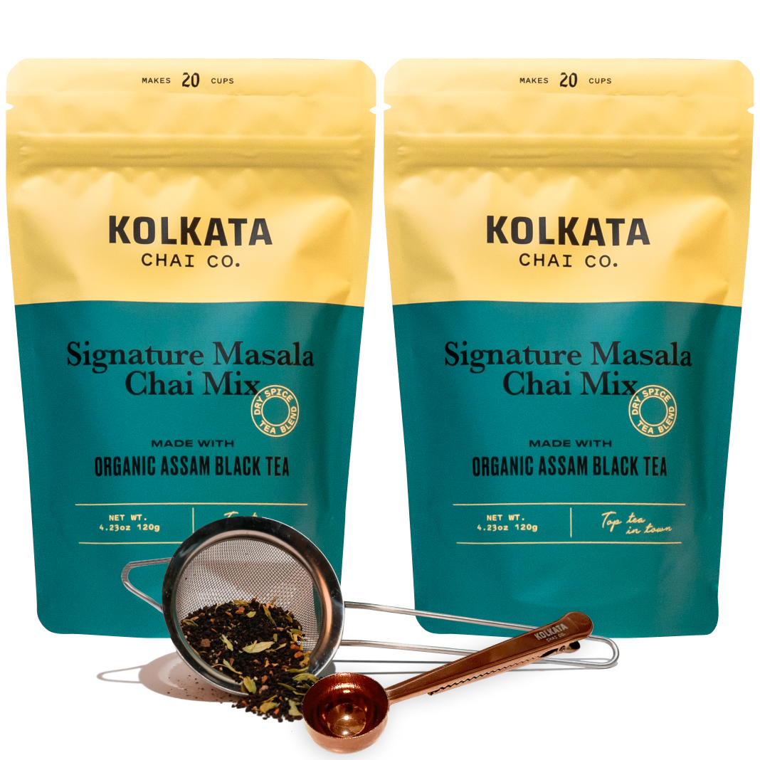 Two bags of chai mix with a tea strainer and measuring spoon.