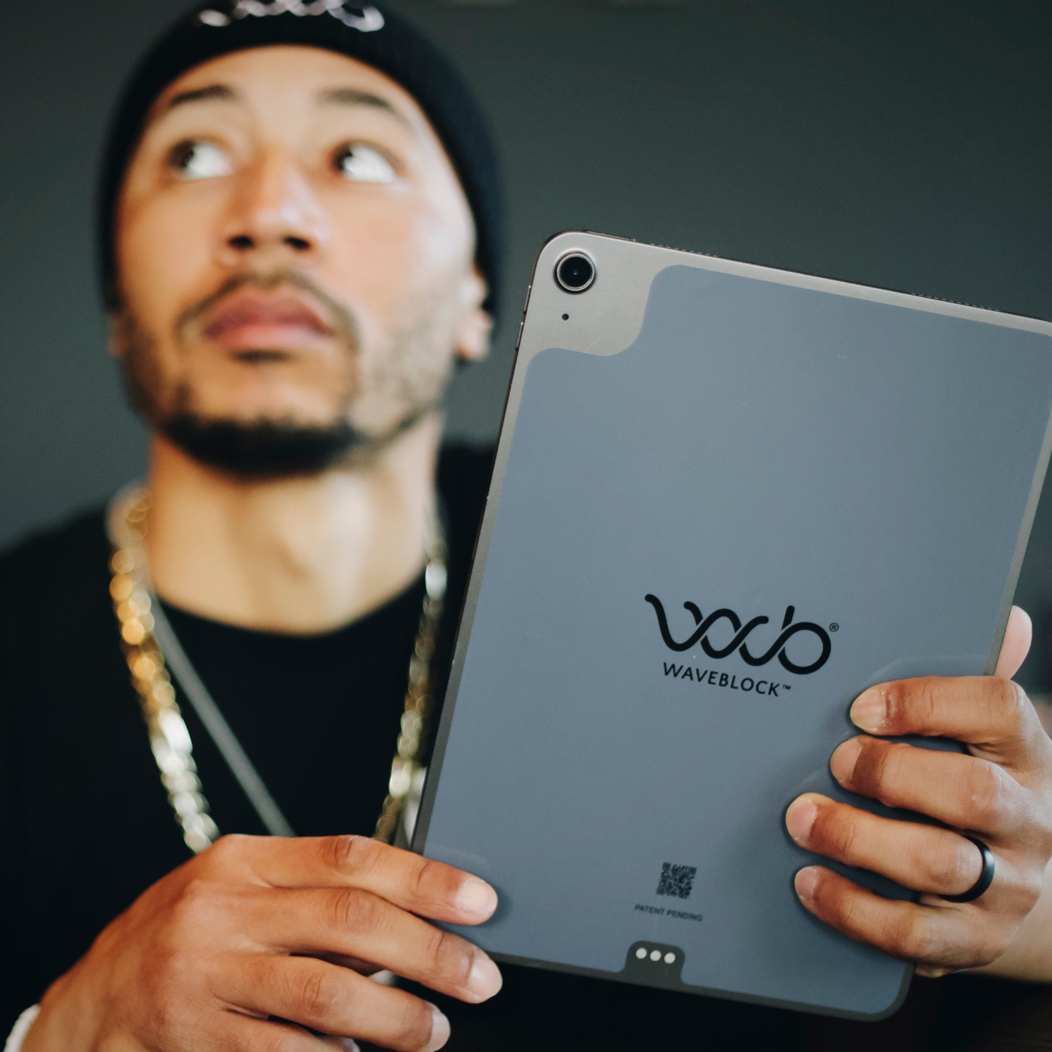 Person holding a tablet with 'Waveblock' logo, looking upwards.