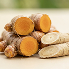 A close-up of fresh turmeric roots, some sliced to show their orange and pale yellow interiors.