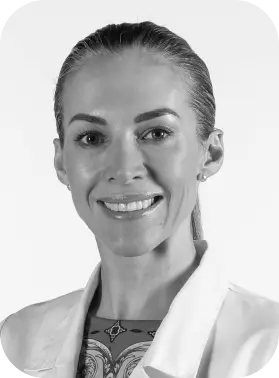 Black and white portrait of a smiling person in a white coat.