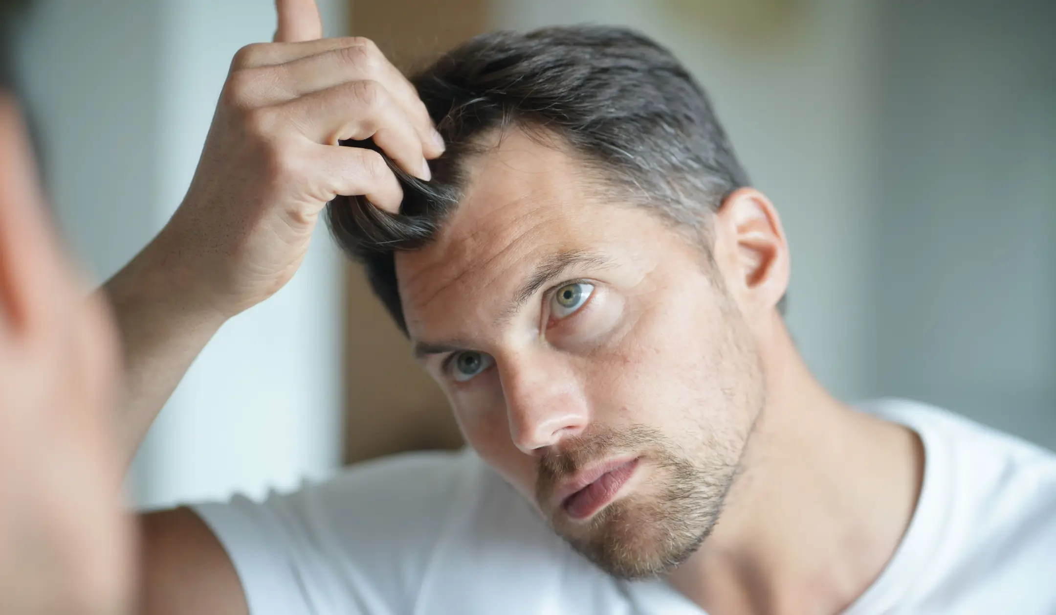 Man examining his hairline in the mirror.