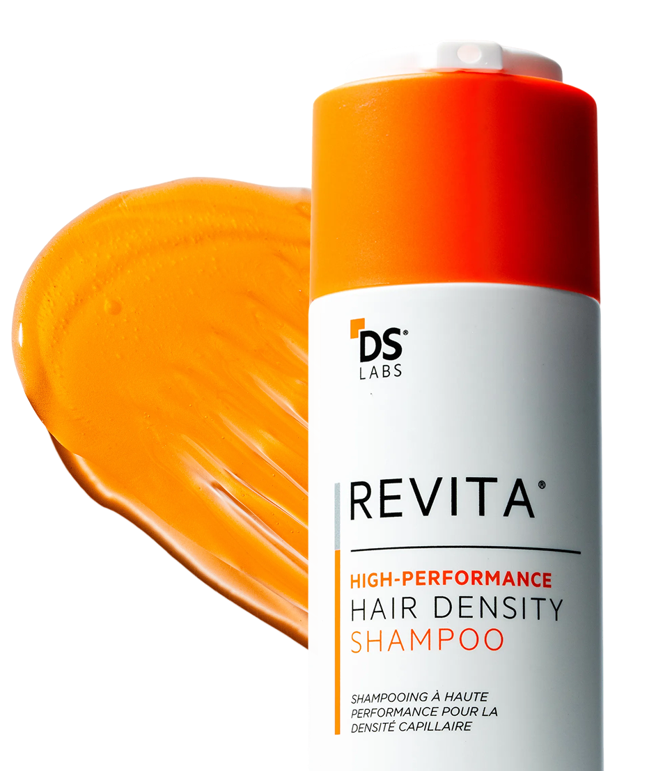 A bottle of DS Labs Revita shampoo with a smear of the orange product against a black background.