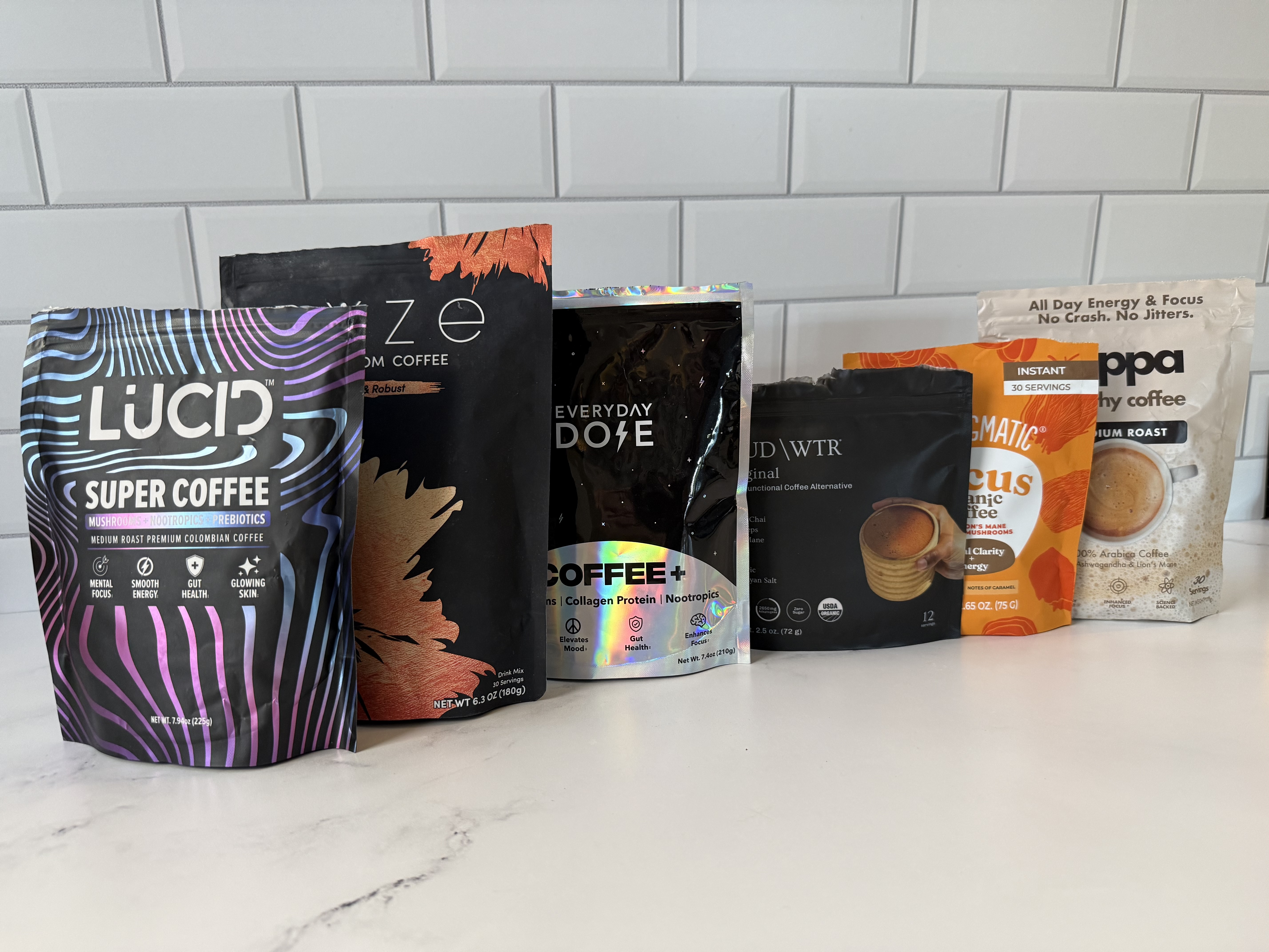 A pouch of Lucid Super Coffee arranged with an iced drink, a scoop, and various mushrooms on pink blocks.