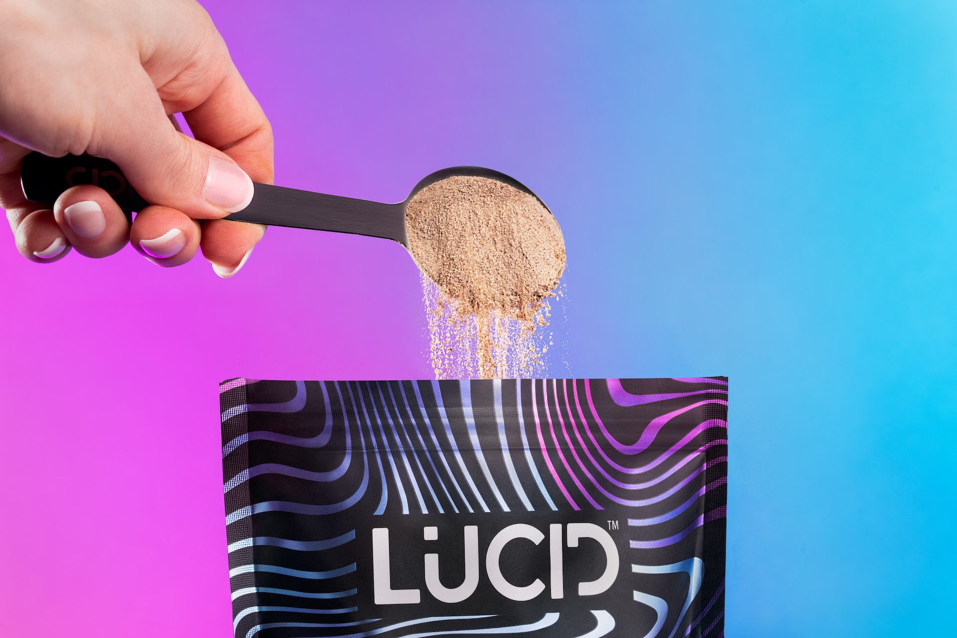 A pouch of Lucid Super Coffee arranged with an iced drink, a scoop, and various mushrooms on pink blocks.