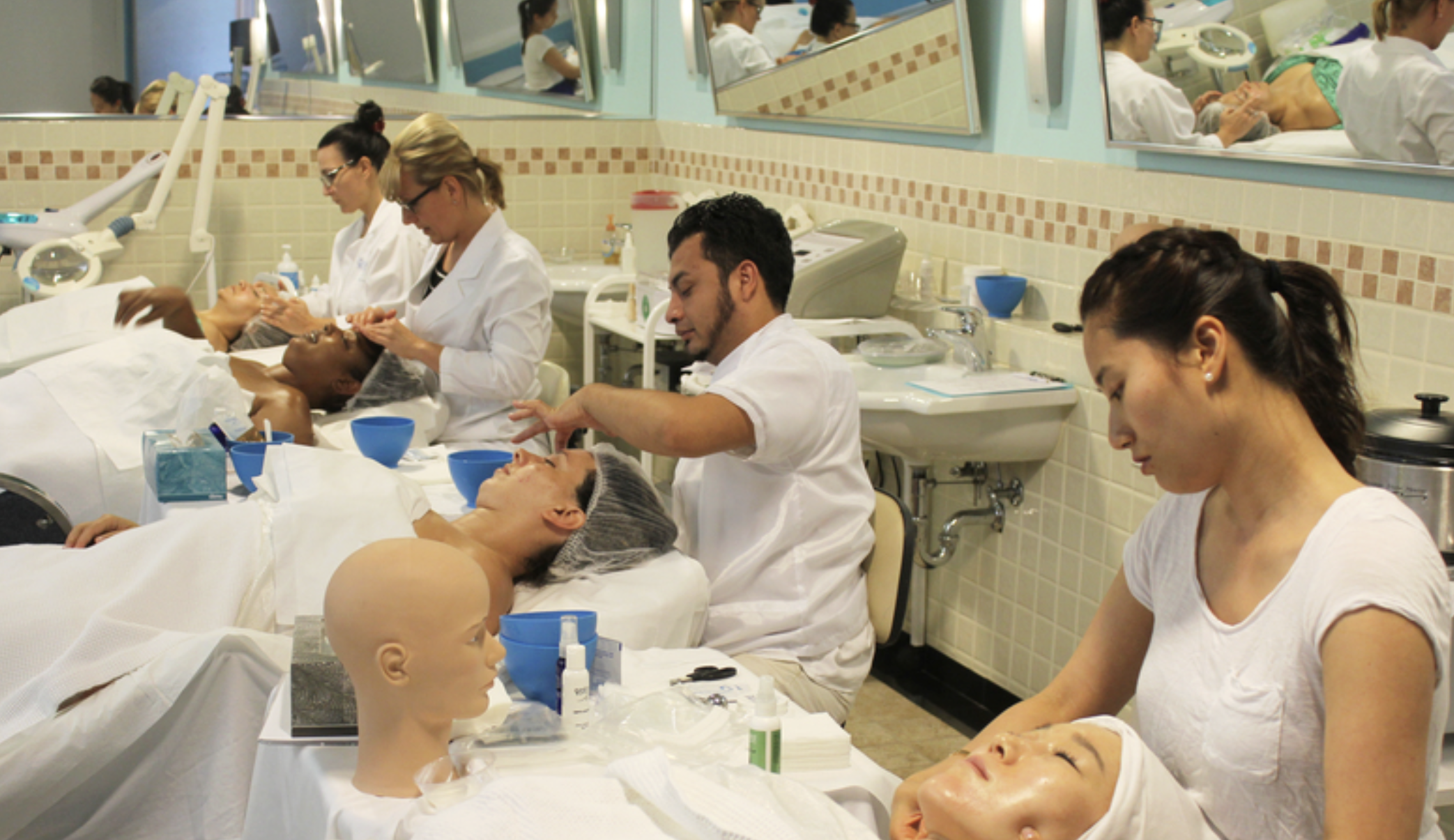 Students in an esthetician class practice giving facials to clients and on mannequin heads.