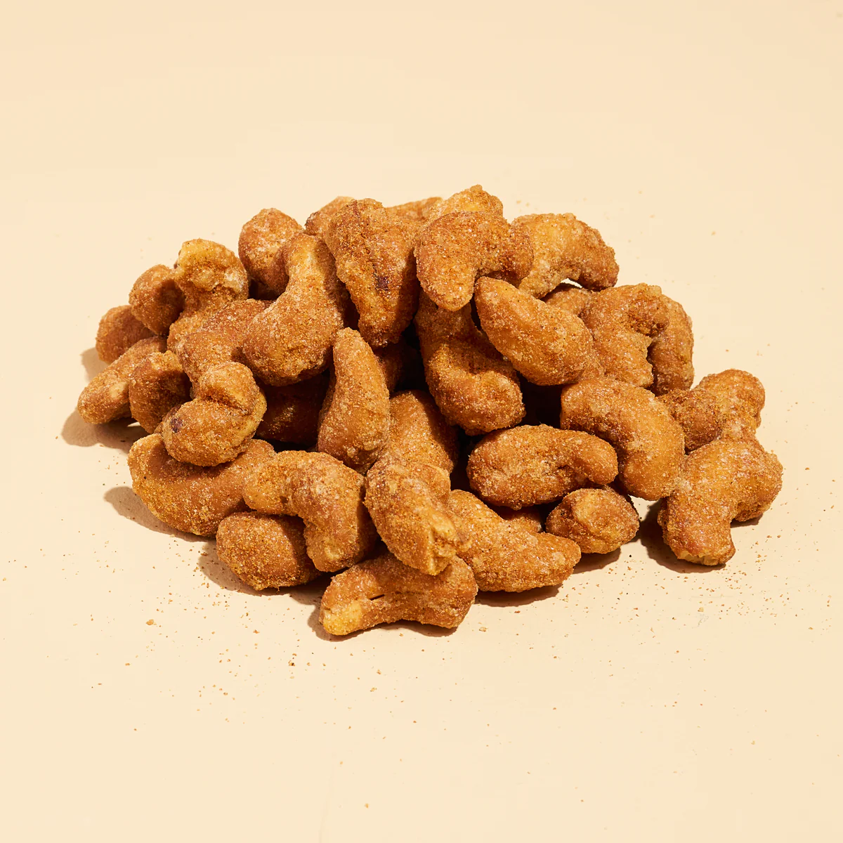 A pile of seasoned cashew nuts on a beige background.