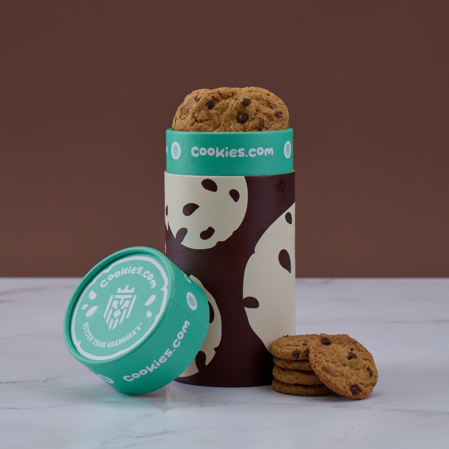 Stack of chocolate chip cookies in a decorative tube labeled 'cookies.com.'