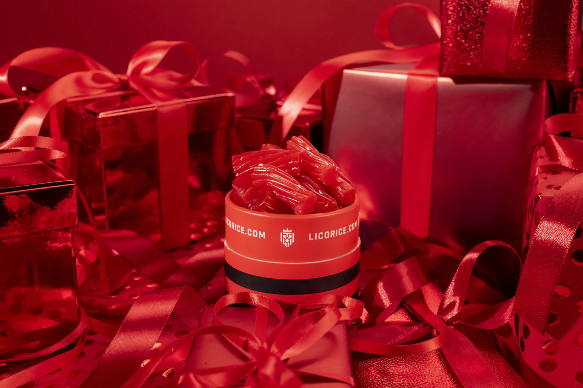 Red licorice container surrounded by red gift boxes and ribbons.