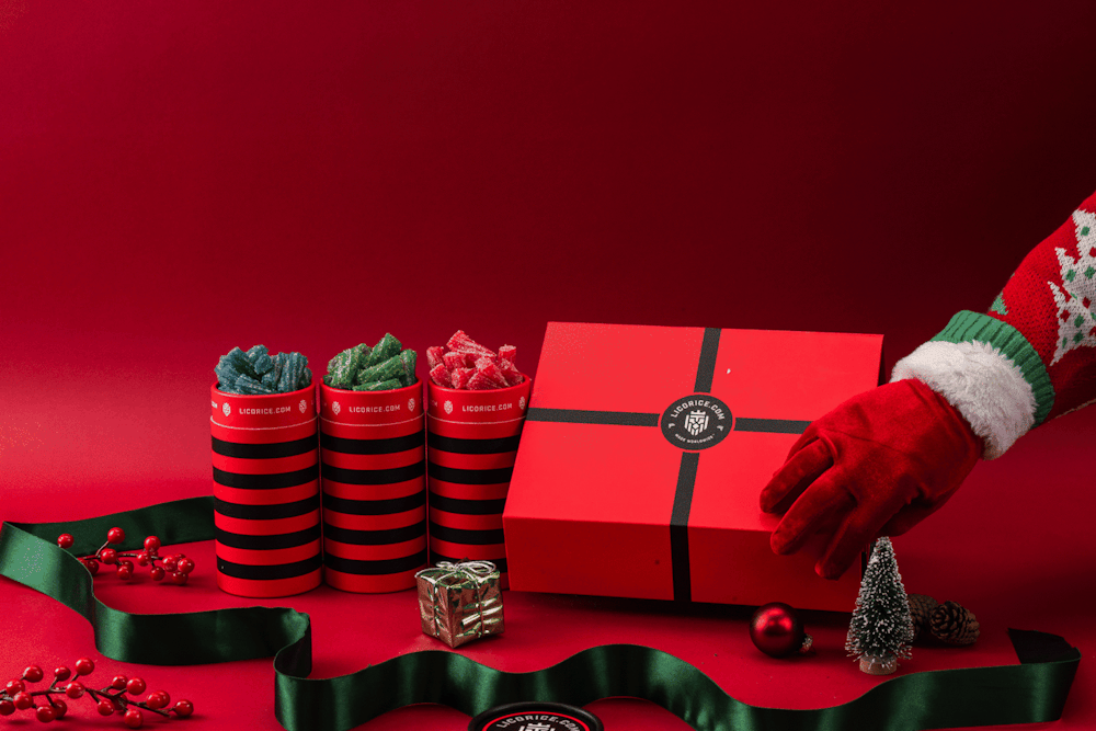Festive red box and candy jars with holiday-themed decorations on a red background.