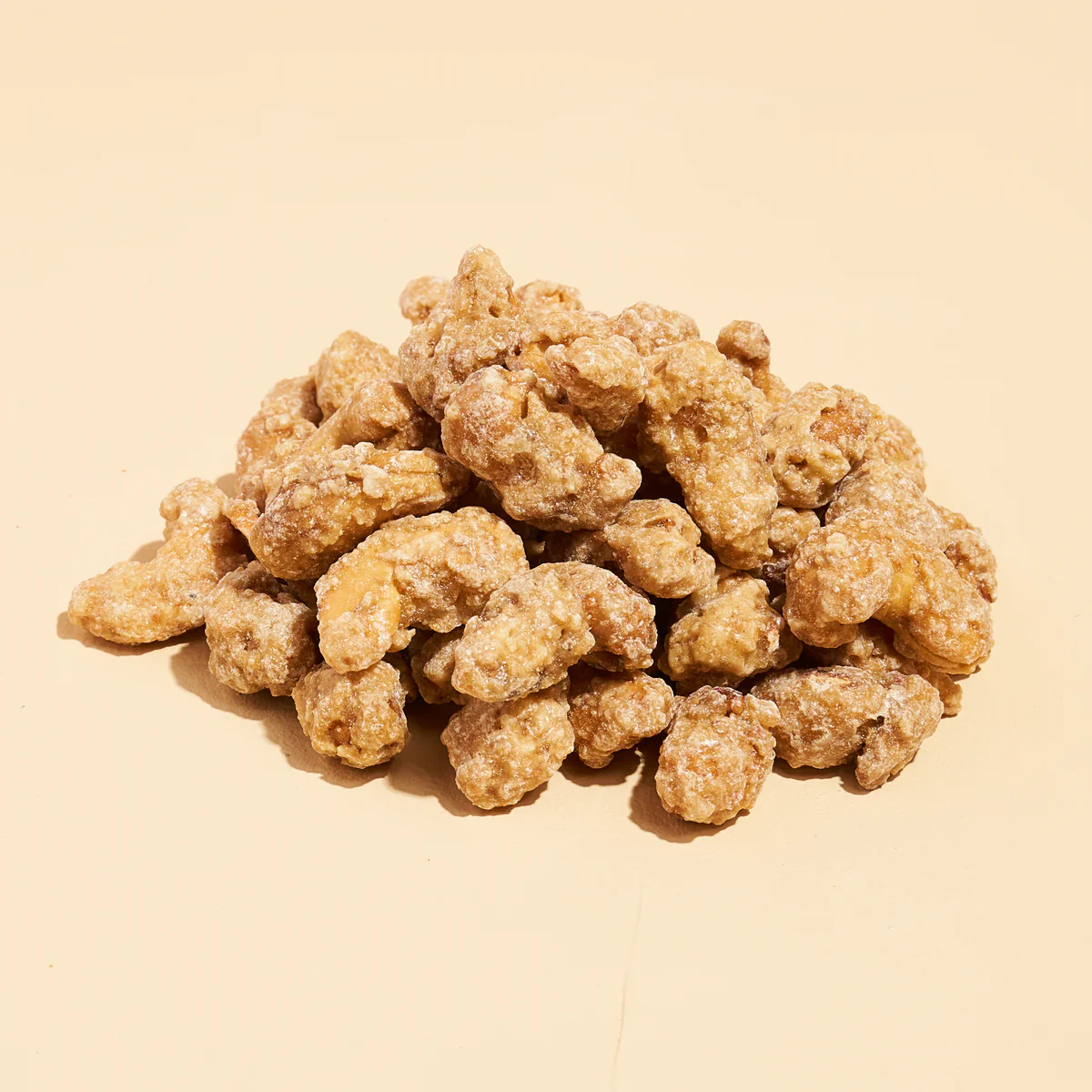 Pile of sugar-coated walnuts on a beige background.