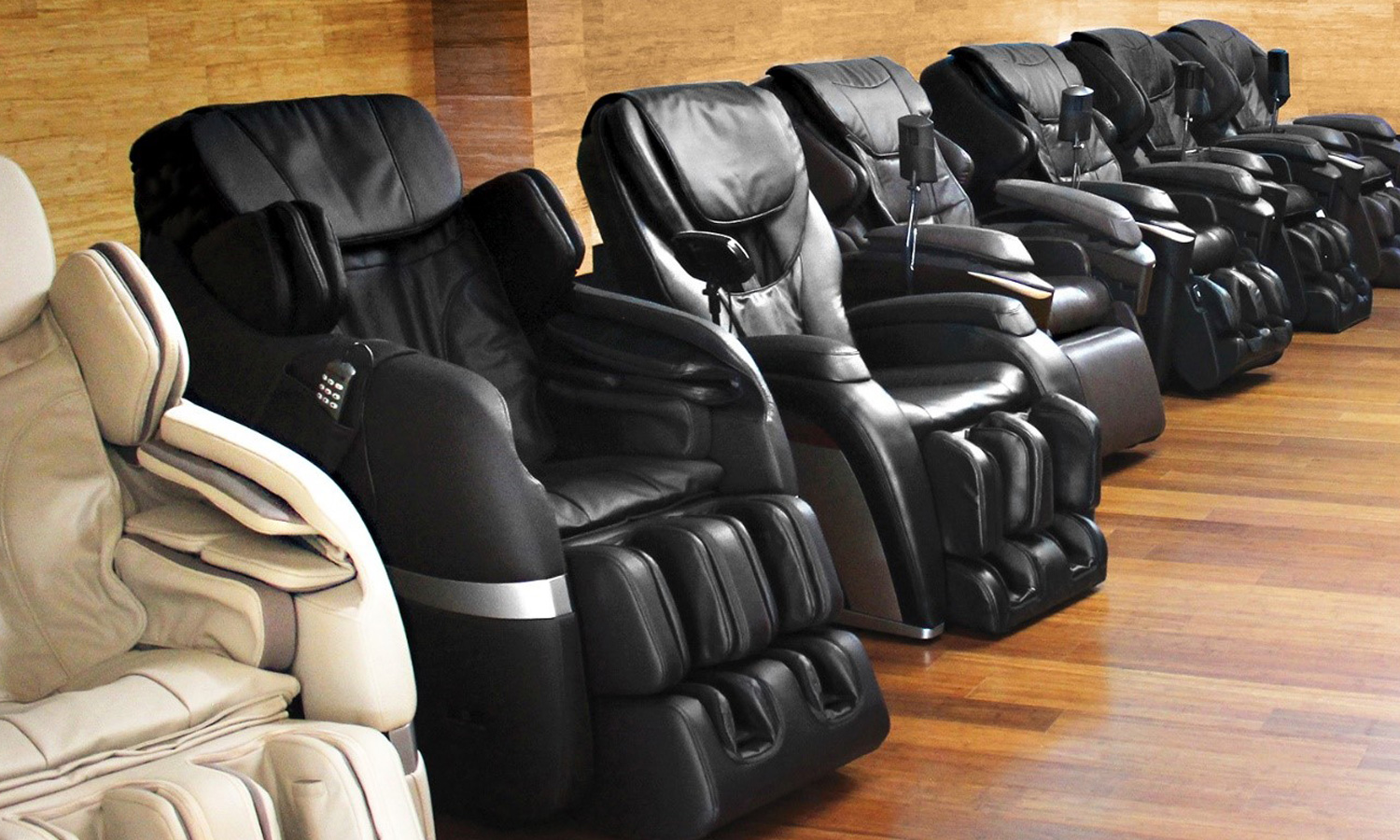 Row of black and beige massage chairs on wooden floor.