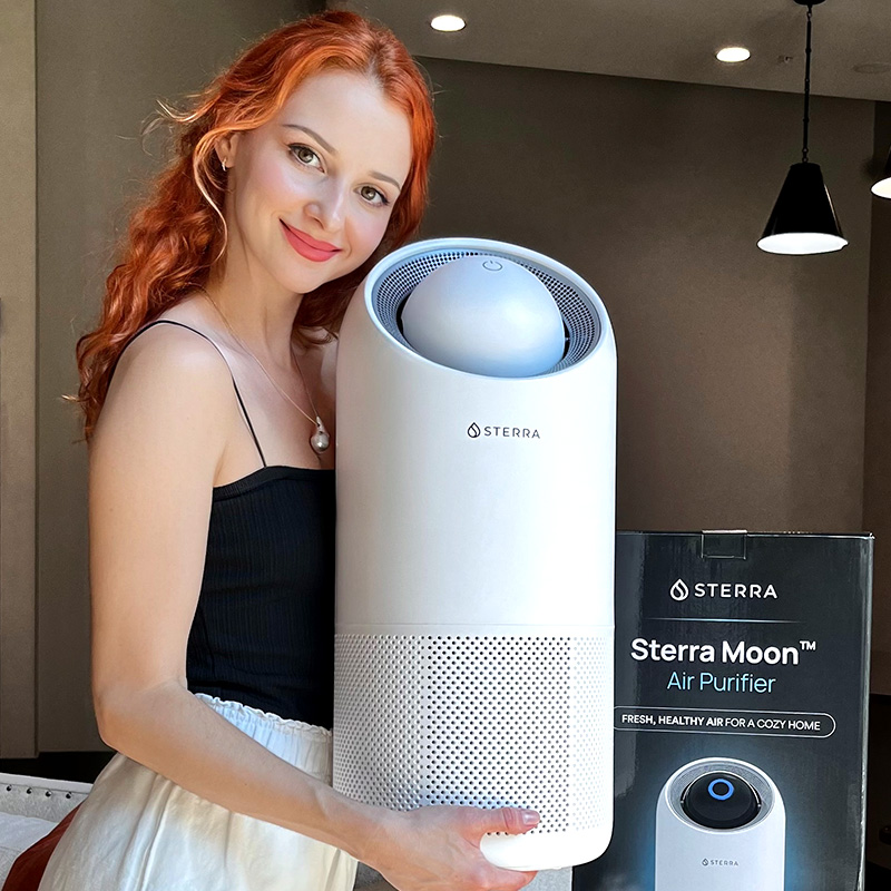 Person holding a Sterra Moon air purifier with packaging box.