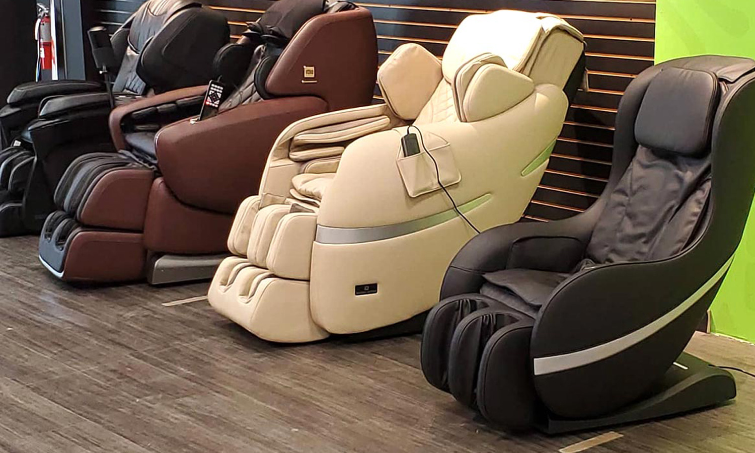 Four massage chairs in different colors lined up in a showroom.