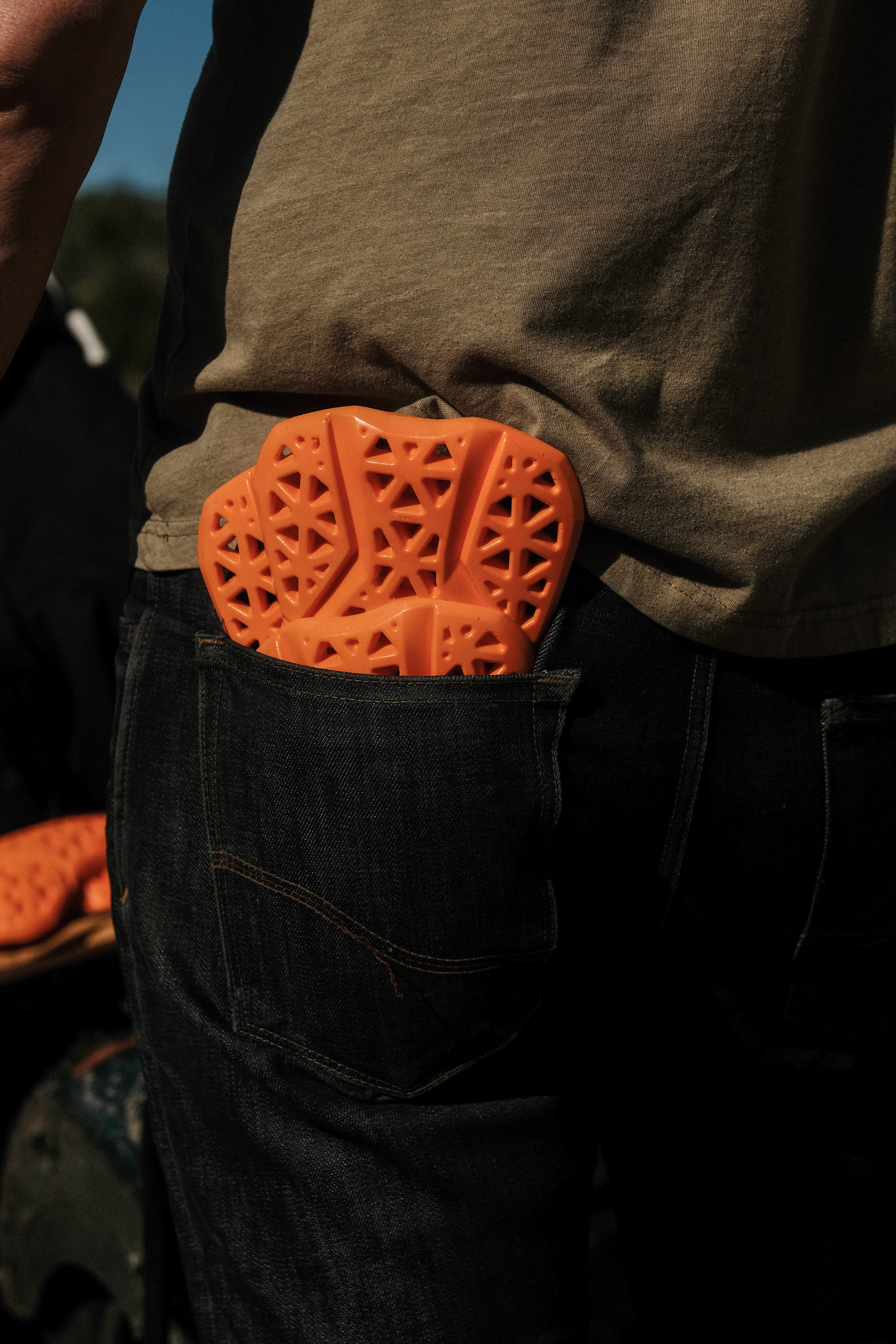 Orange protective gear in a person's back pocket.
