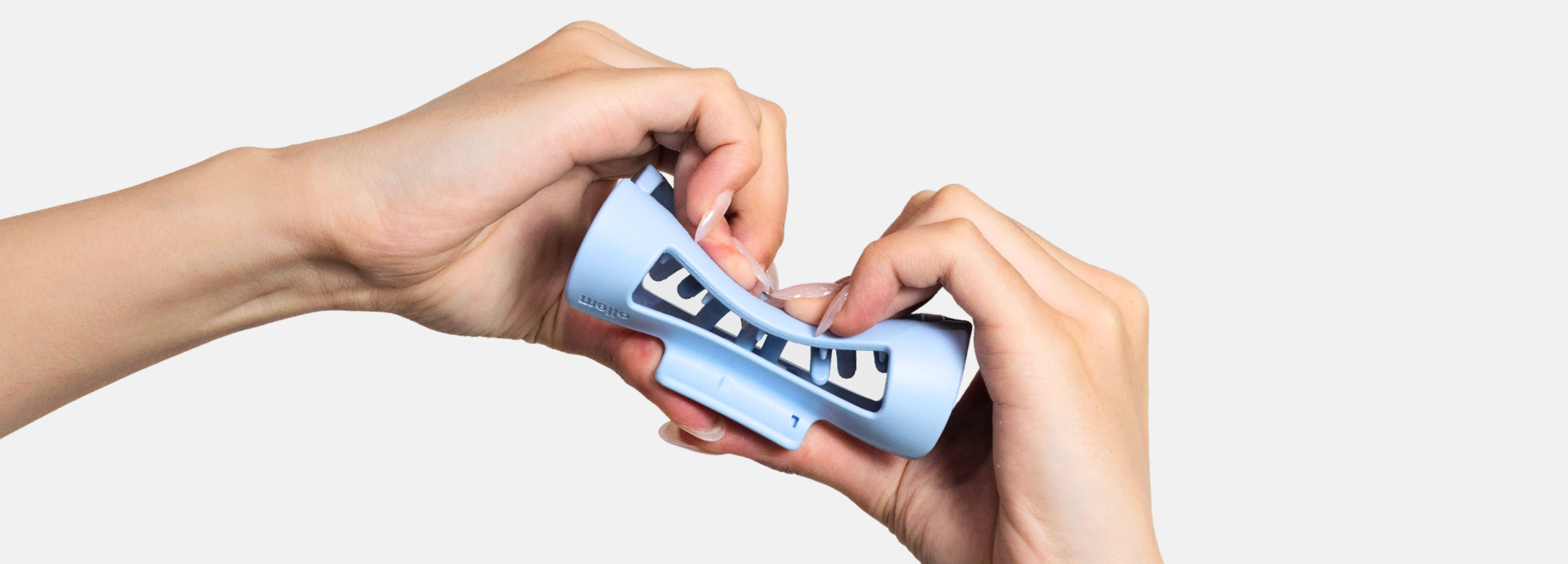 Two hands with long nails bending a flexible light blue plastic object against a white background.