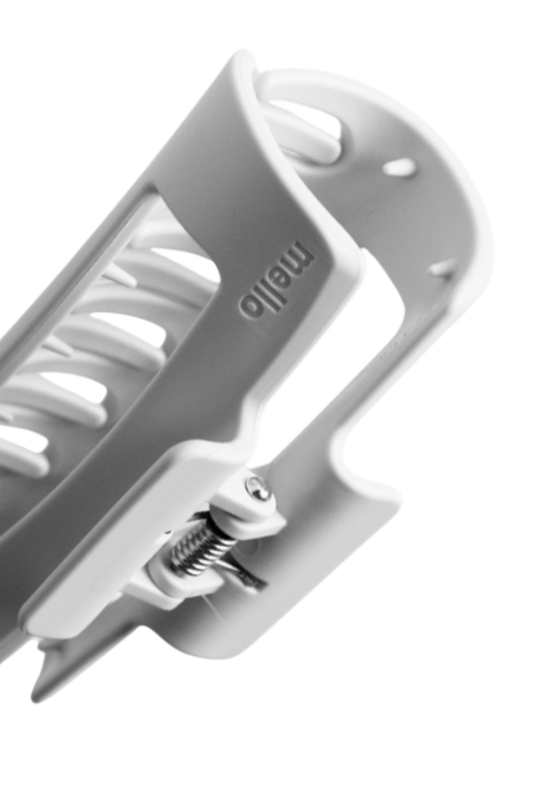 A close-up, black and white photograph of a white hair claw clip with the brand name 'mello'.