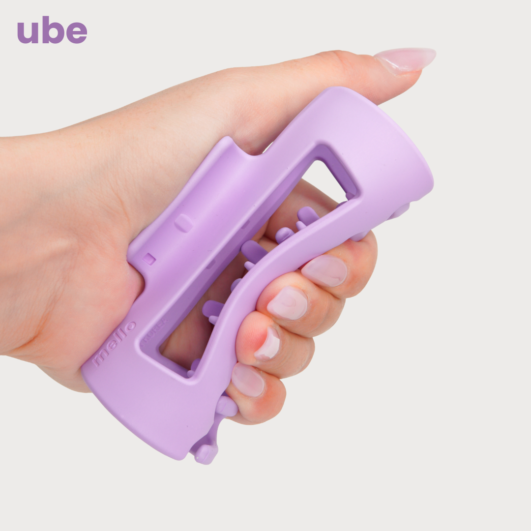 Hand holding a purple grip exercise tool labeled 'ube.'