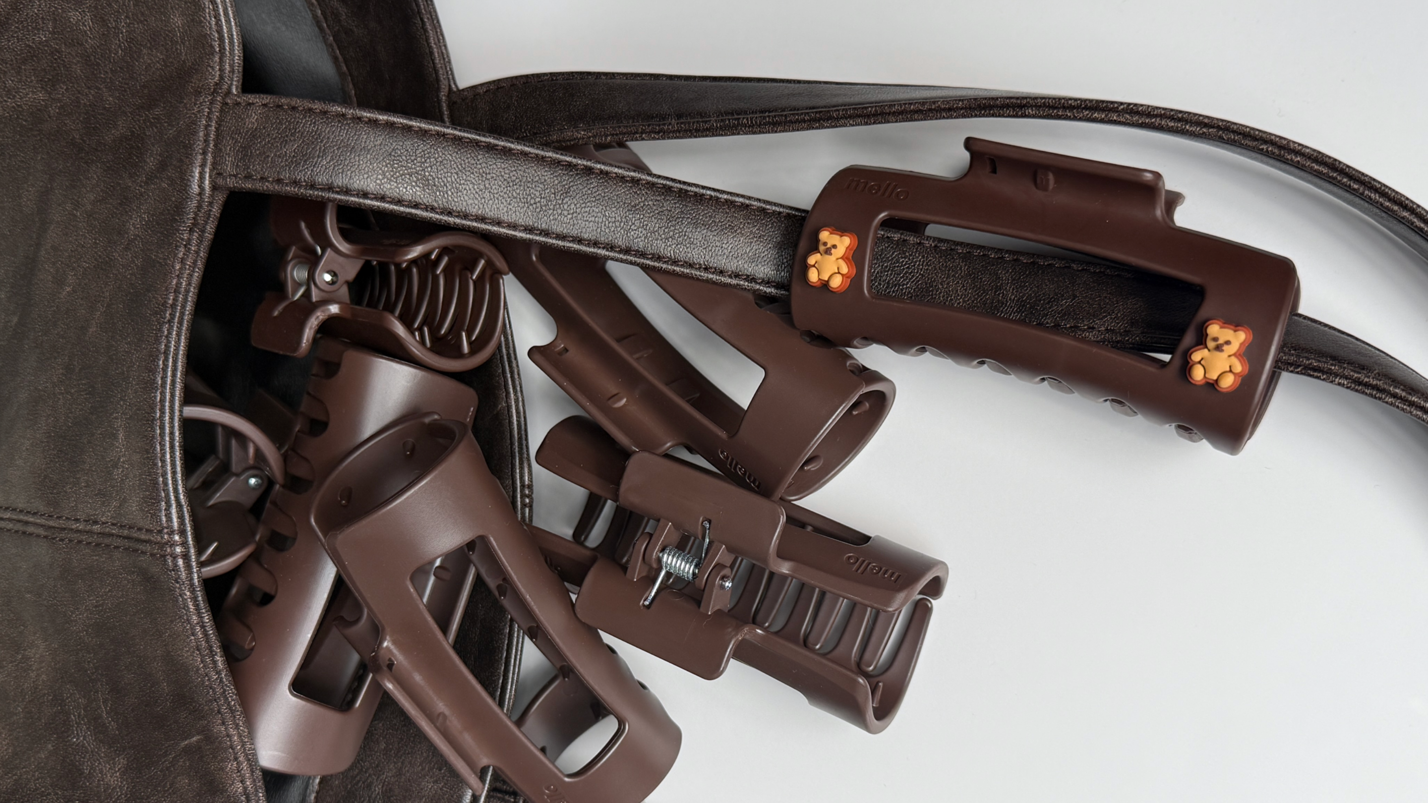 A close-up of brown plastic clips with teddy bear charms spilling from a brown leather bag.