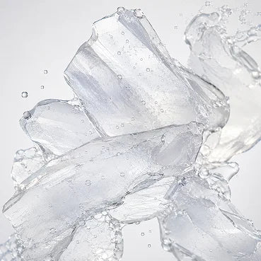 Clear shards of ice with water splashing around them against a light background.
