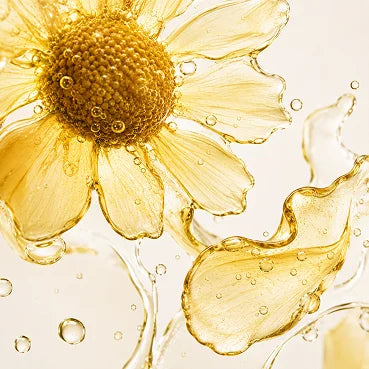 A close-up of a yellow flower made of a golden liquid with bubbles, against a light background.