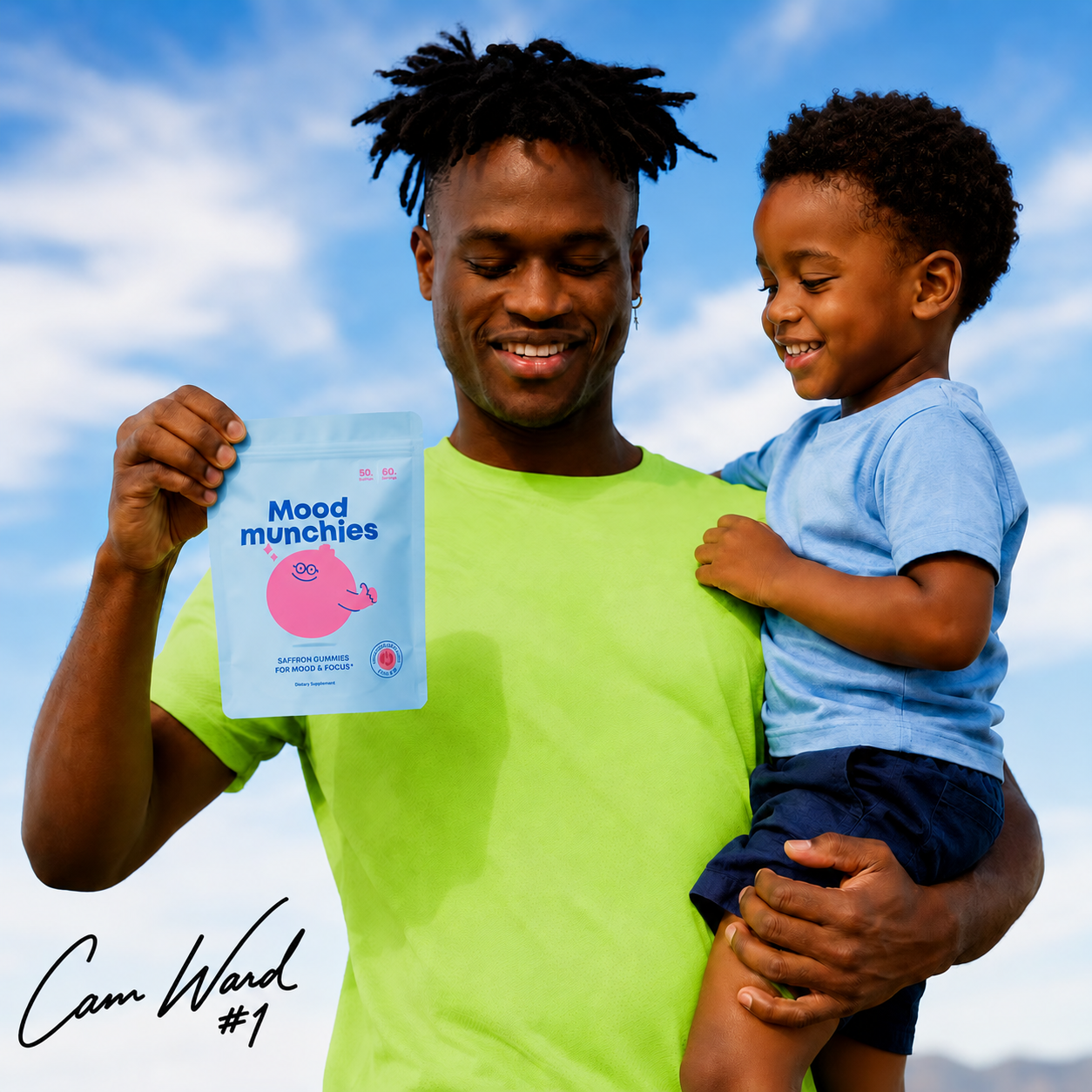 A smiling man holds a young boy and a pouch of Mood Munchies against a blue sky.