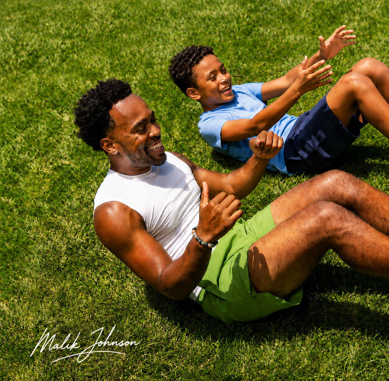 A man and a boy smile as they do sit-ups together on a sunny, green lawn.