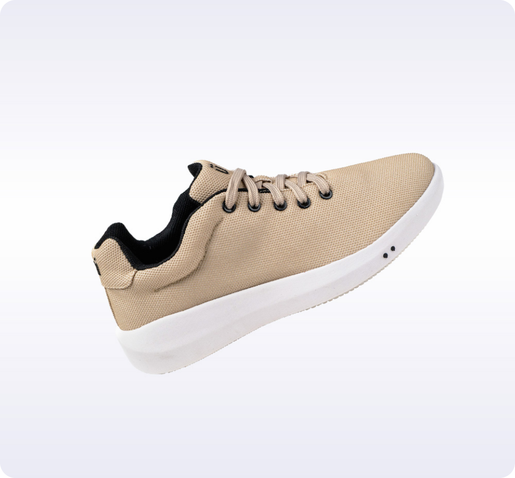 Tan sneaker with white sole and black laces on a light background.