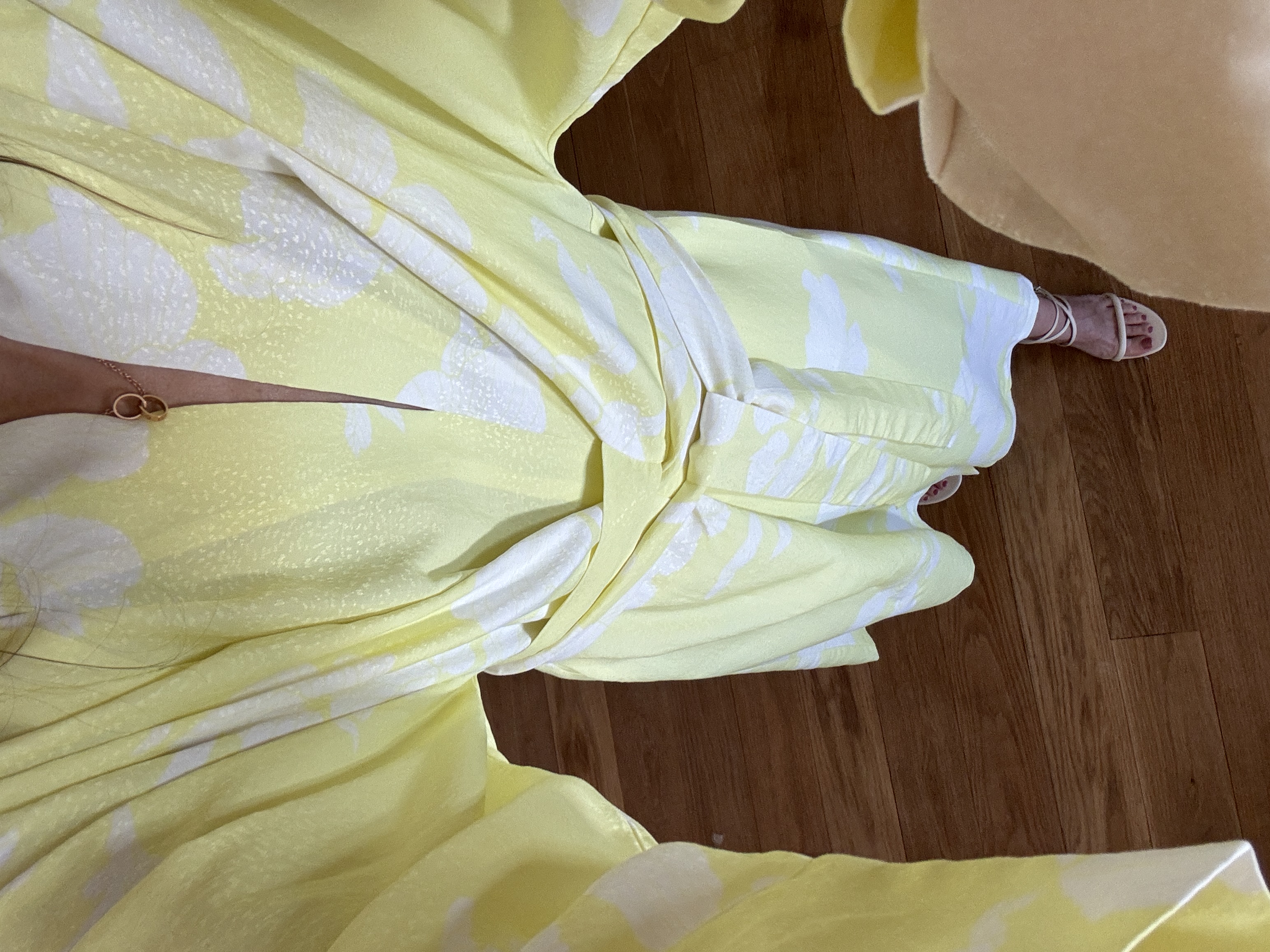 Person wearing a yellow floral robe standing on wooden floor.