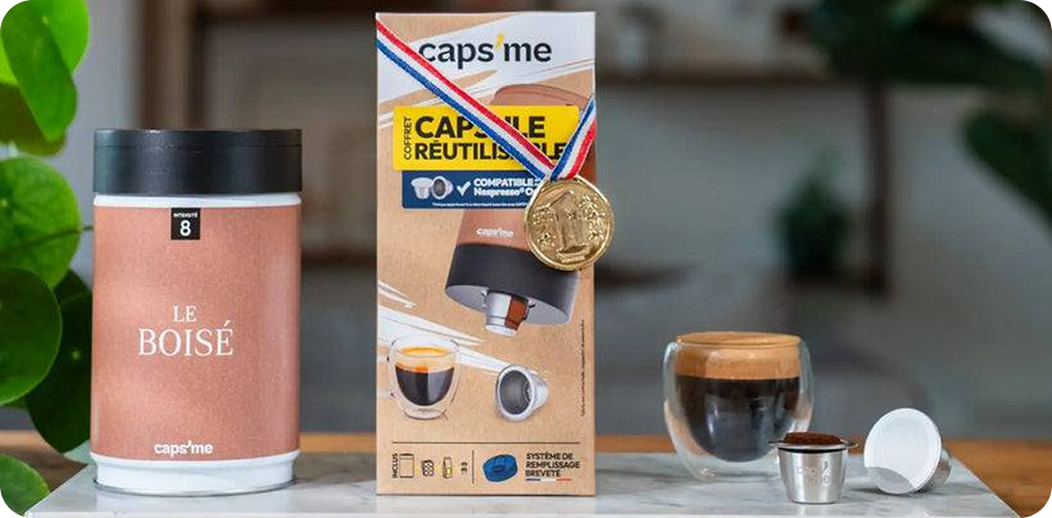 A Caps'me reusable coffee capsule kit with a canister of coffee and a glass of espresso.
