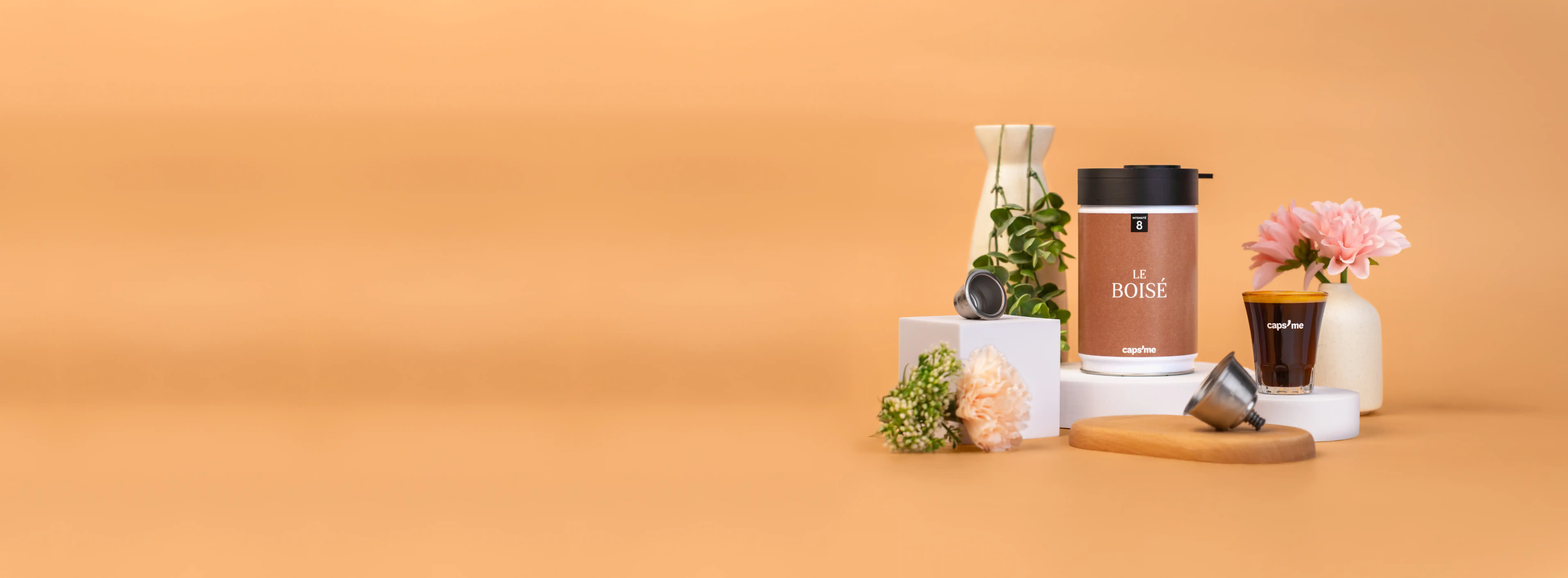 Coffee container, cup, and flowers on a beige background.