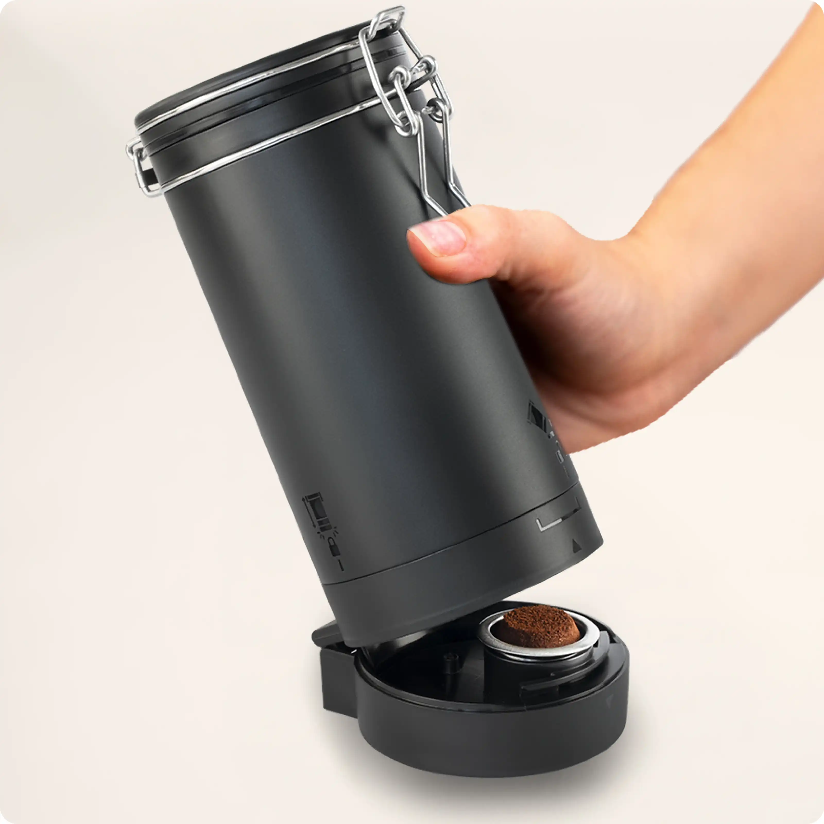 Hand holding a black coffee grinder with a removable base.