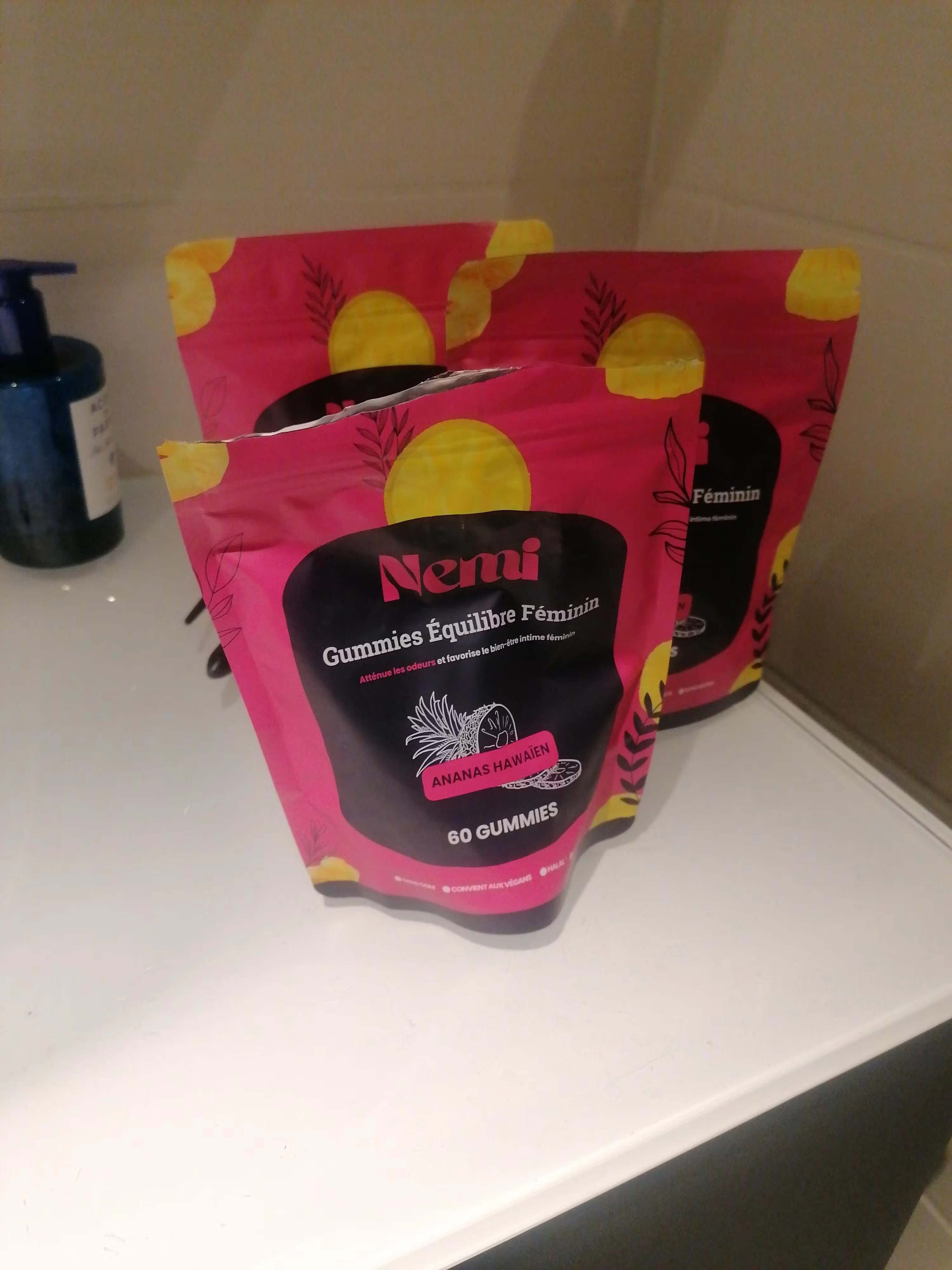 Three pink and yellow bags of gummies on a bathroom counter.