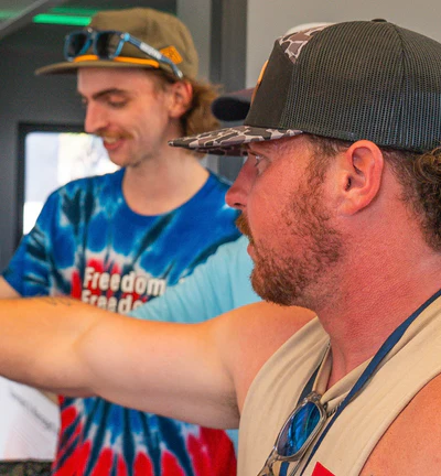 Two men wearing casual clothing and hats, one pointing at something.