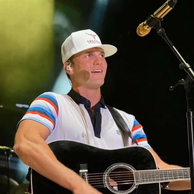 Person playing guitar on stage with microphone.