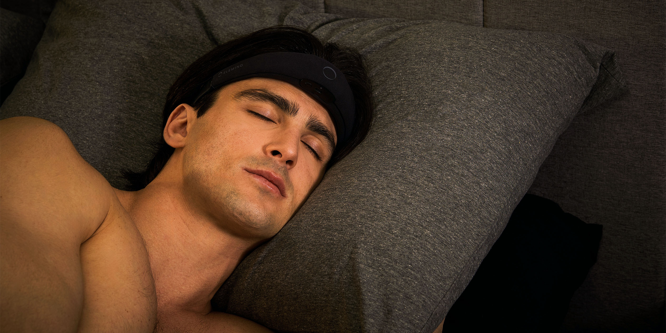Person sleeping on grey pillow, wearing a black headband.