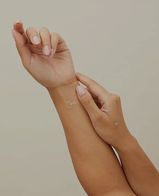 Two hands with small adhesive patches on the wrists.
