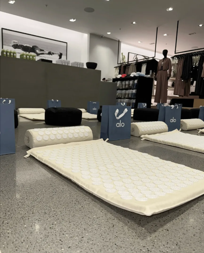 Acupressure mats and pillows are laid out on the floor inside an Alo retail store.