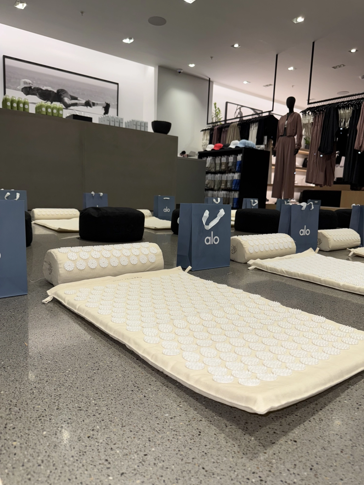 Yoga mats and cushions arranged with alo gift bags in a retail store.
