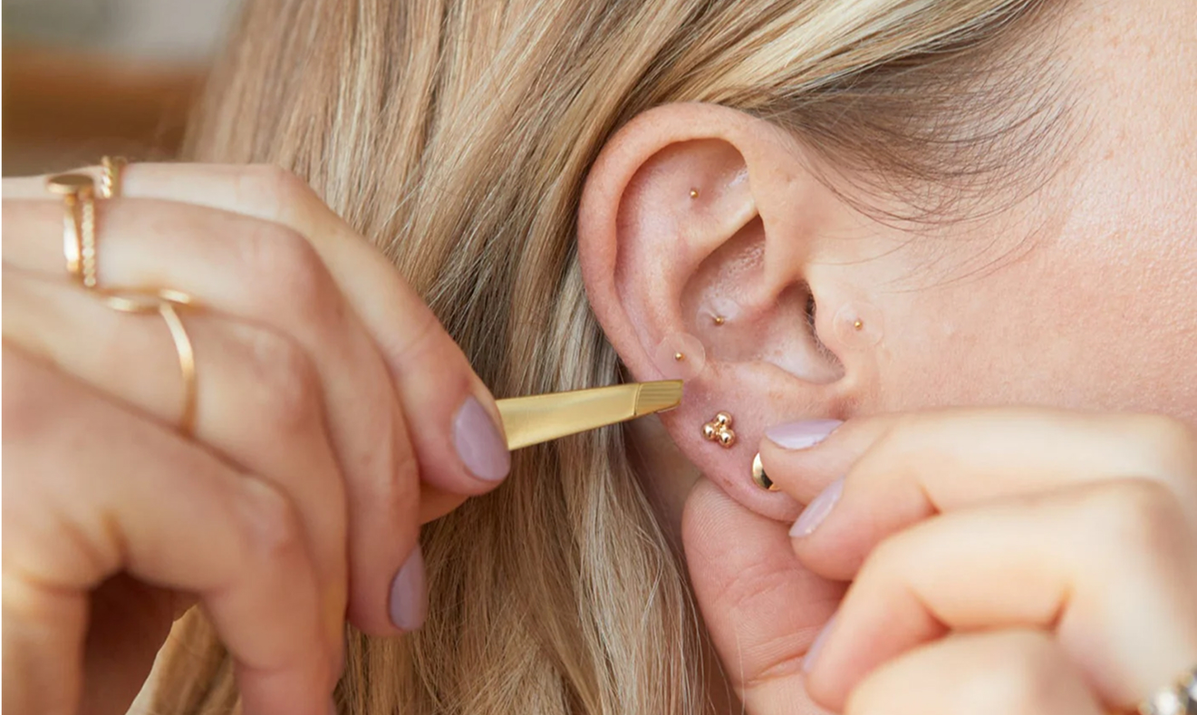 Close-up of a person inserting an earring into a pierced ear.