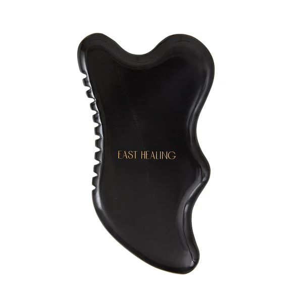 Black gua sha tool with 'EAST HEALING' text.