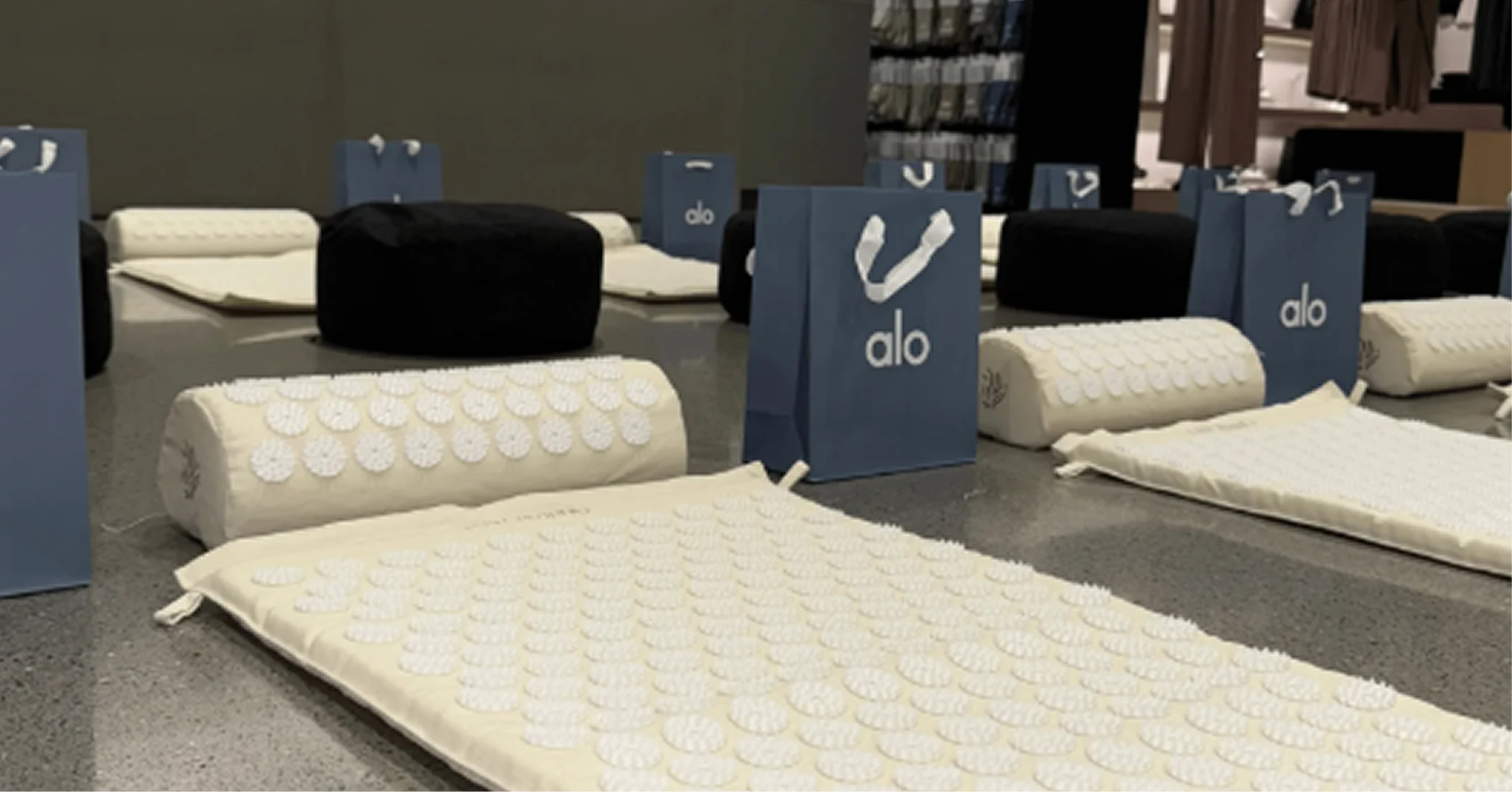 Acupressure mats, pillows, and Alo shopping bags are arranged on the floor of a room.