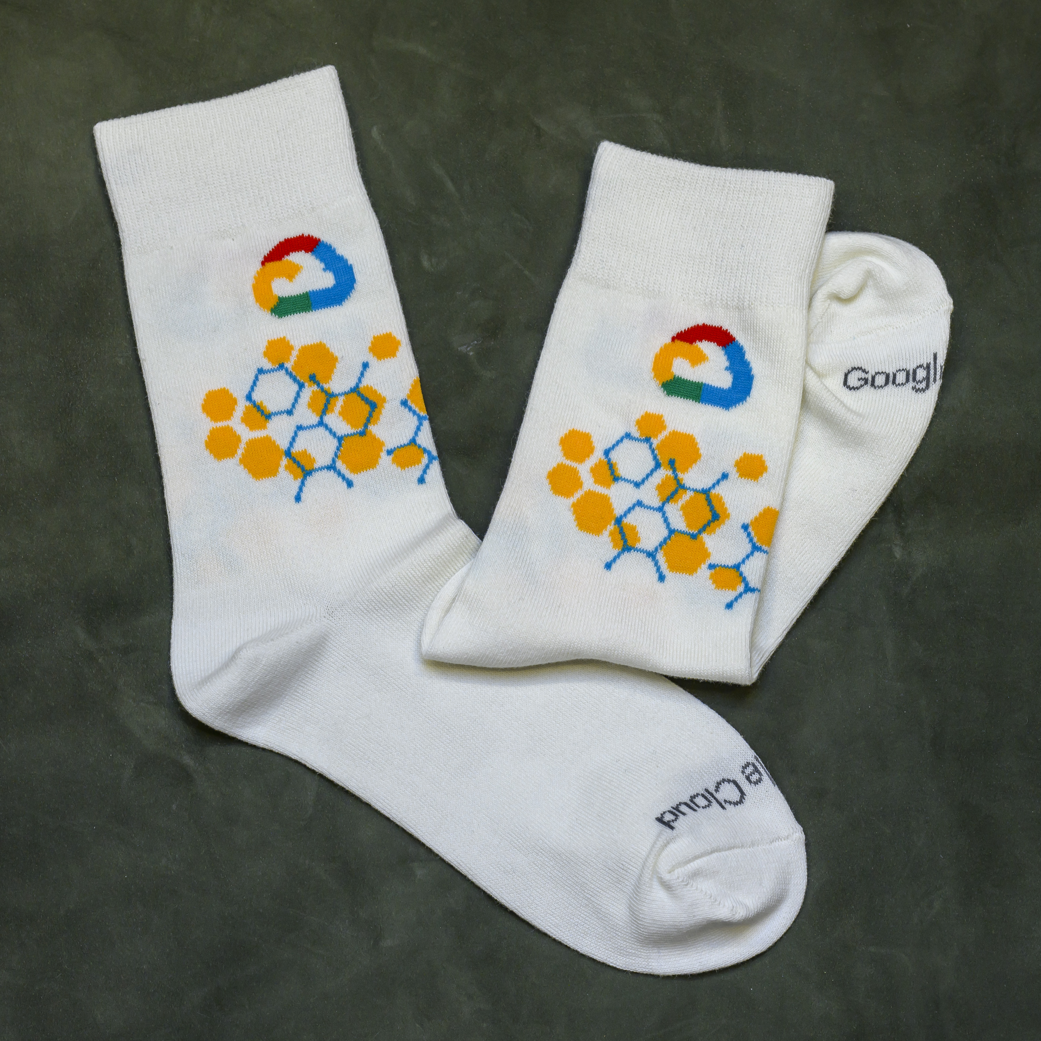 A pair of white socks with the Google Cloud logo and a yellow and blue hexagonal pattern.