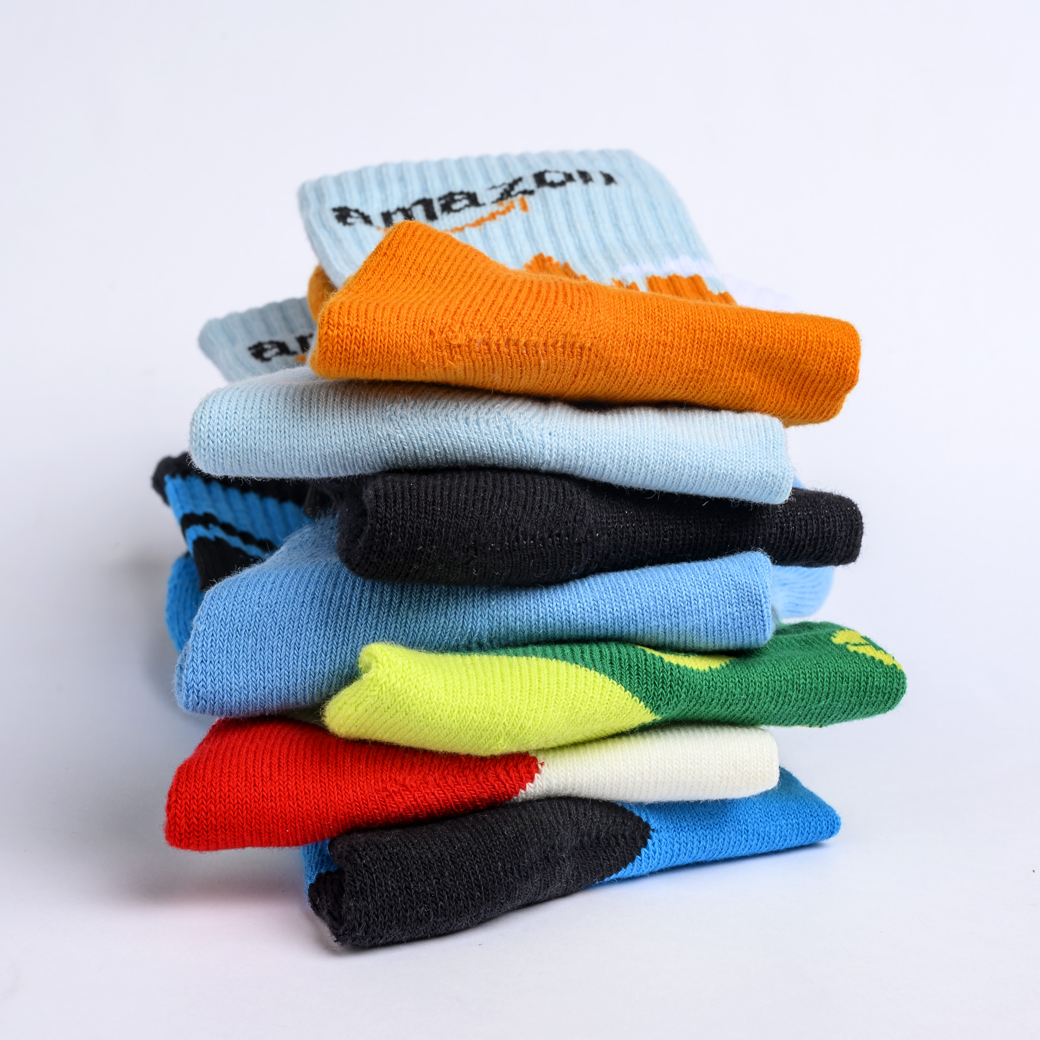 A stack of colorful, folded socks, some with the Amazon logo, against a white background.