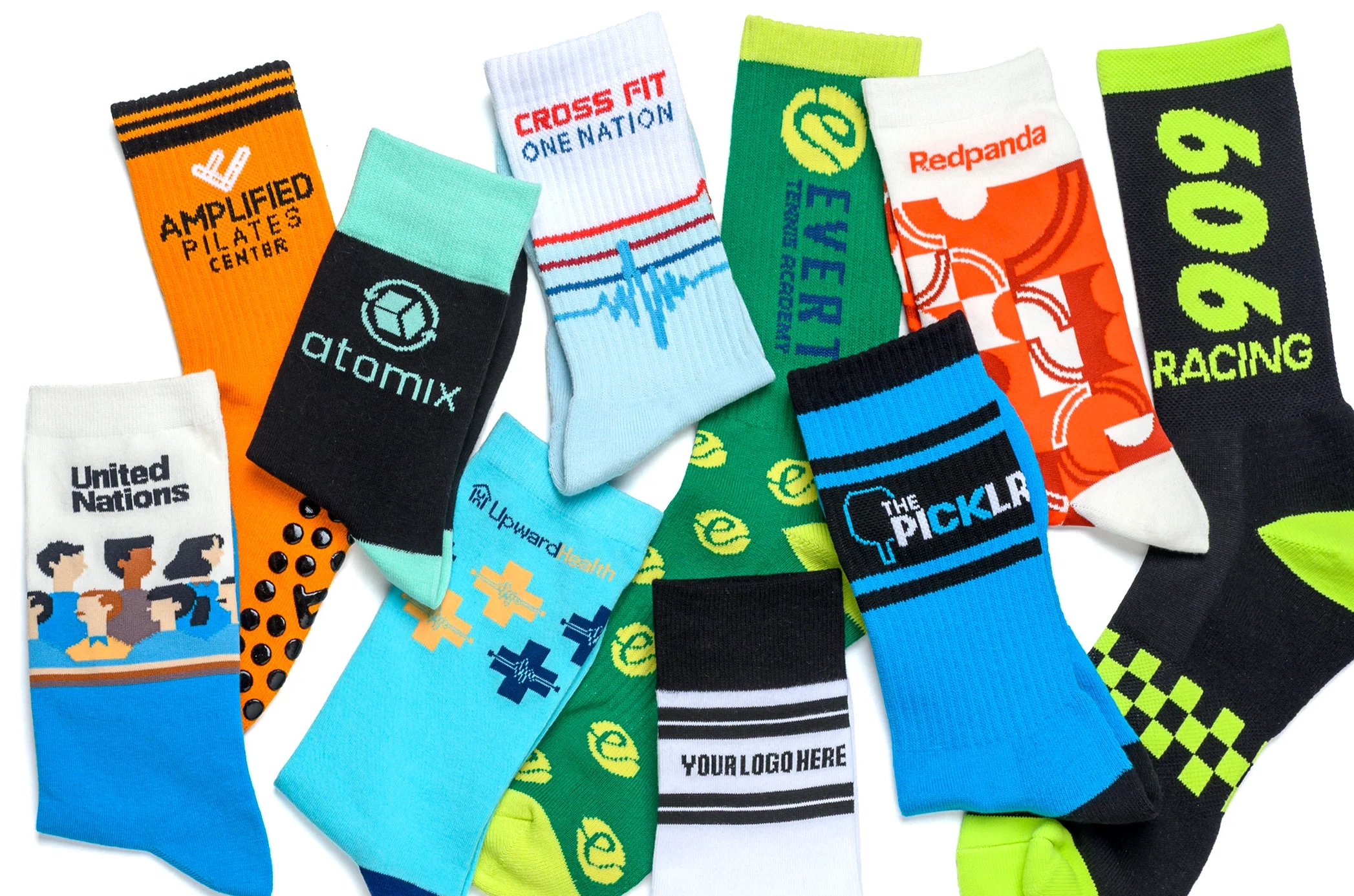 An assortment of colorful, custom-branded athletic socks are laid out on a concrete surface.