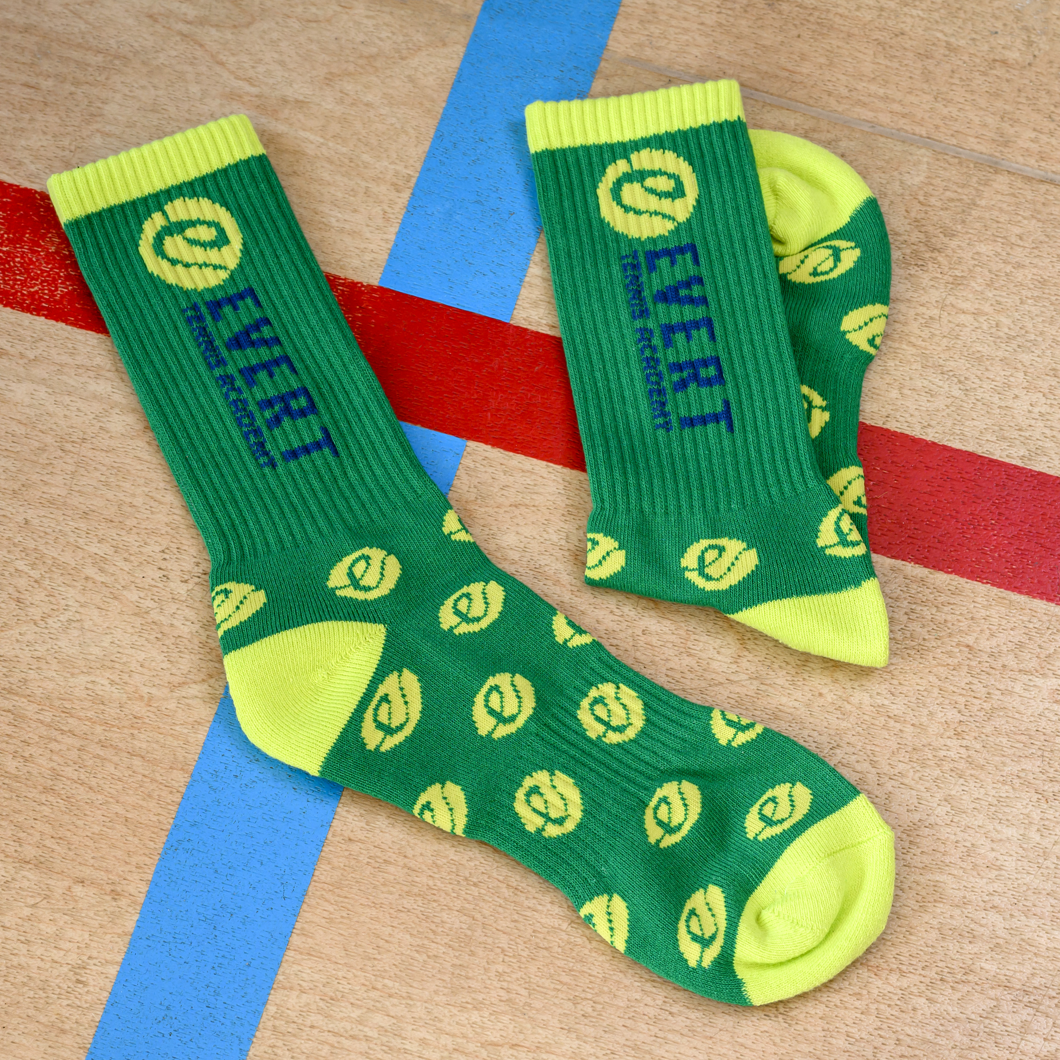 A pair of green and neon yellow Evert athletic socks on a wooden surface with painted lines.