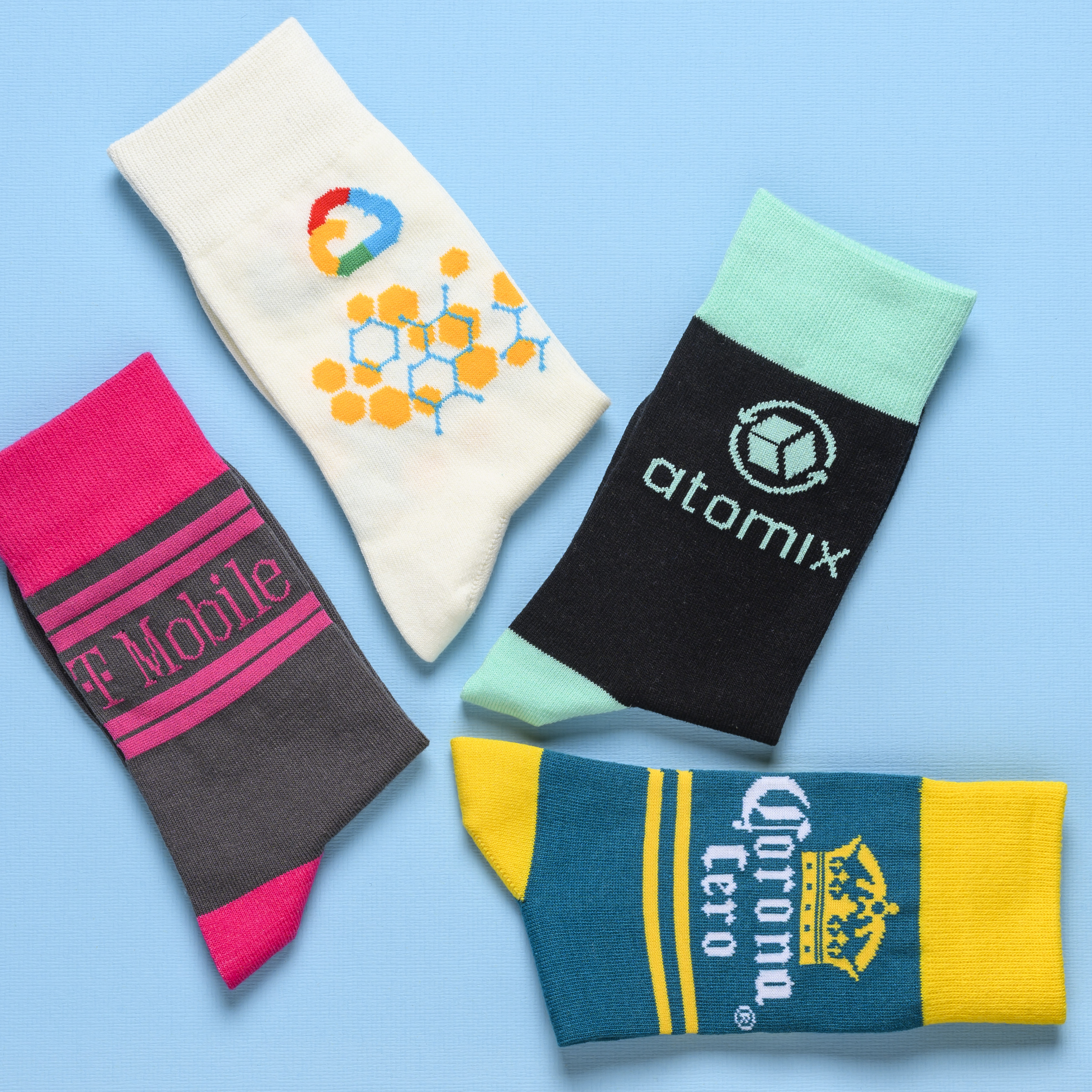 Four pairs of custom branded socks with various company logos laid out on a light blue background.